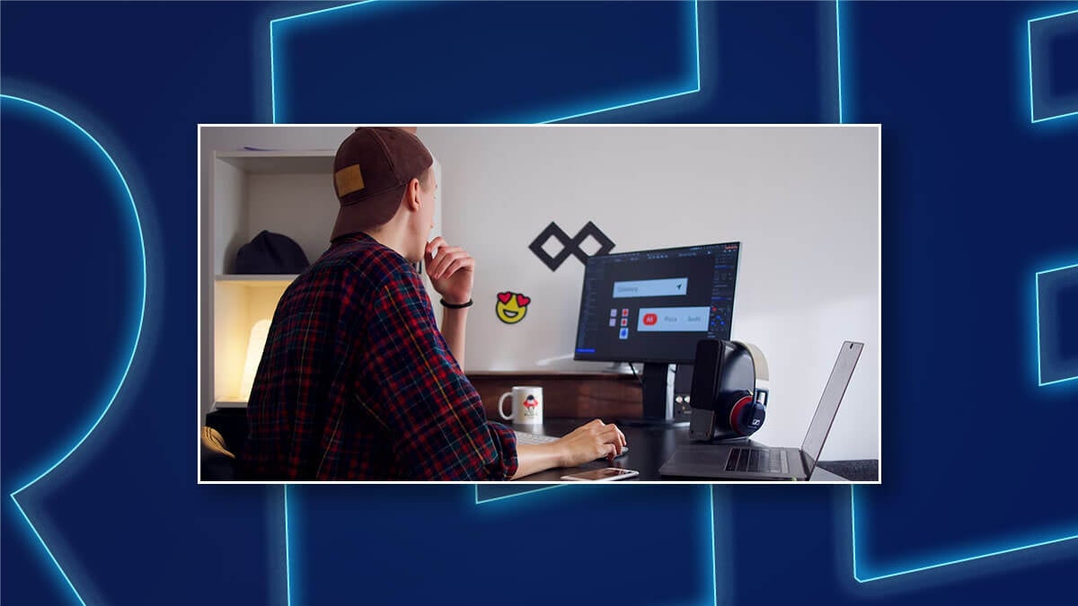 Person working at a desk with a monitor and laptop in a home office.