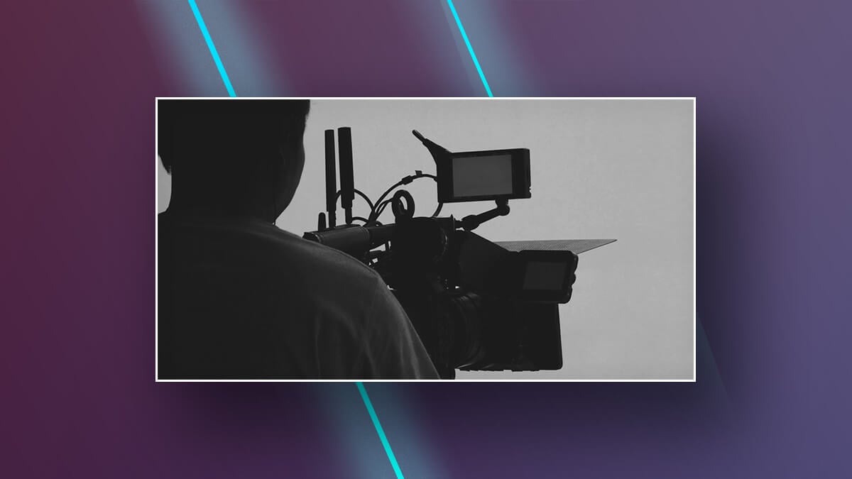 Silhouette of a person operating a professional video camera.
