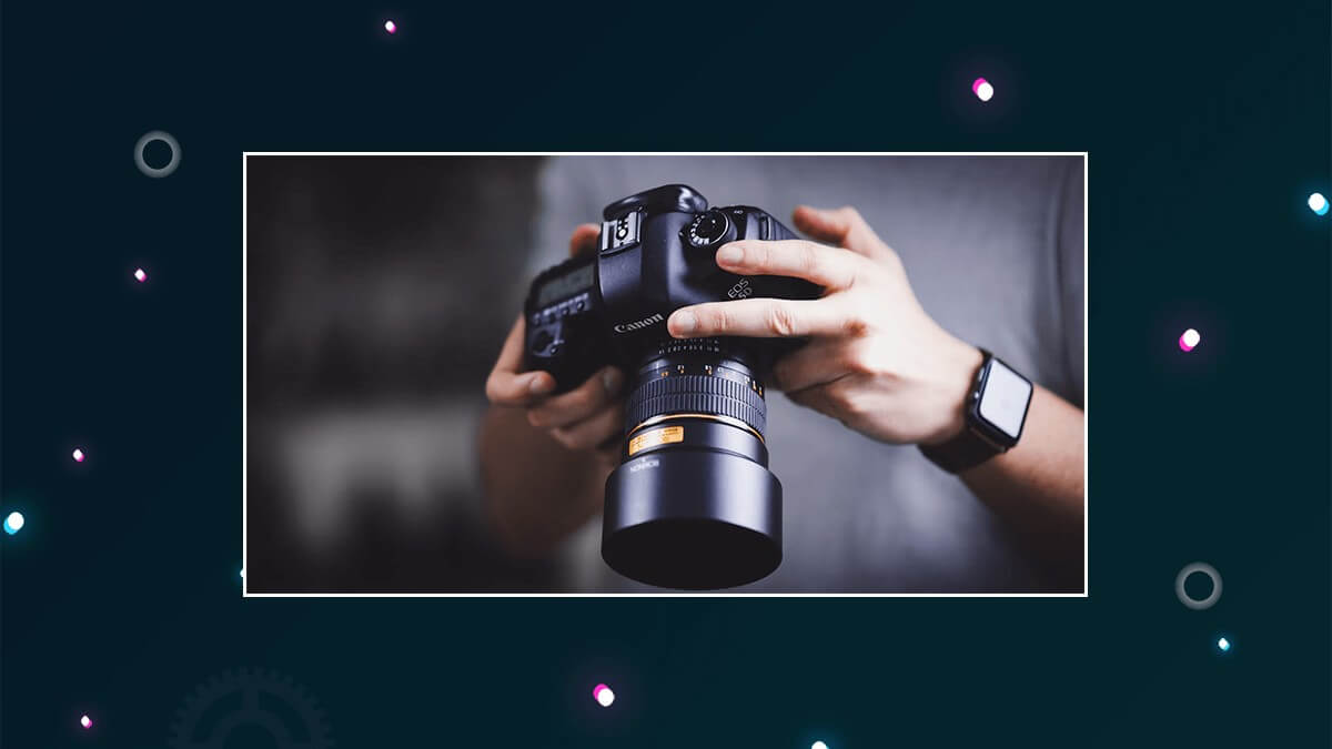 Person holding a Canon DSLR camera with a long lens.