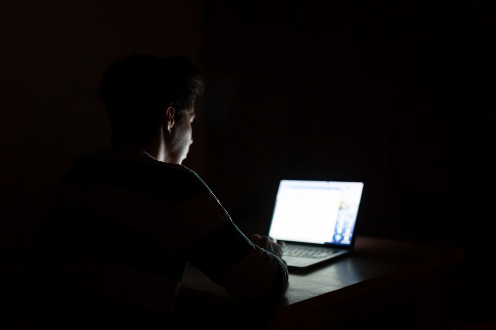 Person using a laptop in a dark room.