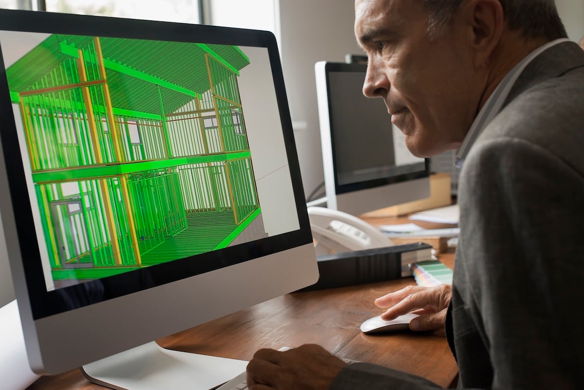 Architect reviewing a 3D structural model of a building frame on a desktop computer.