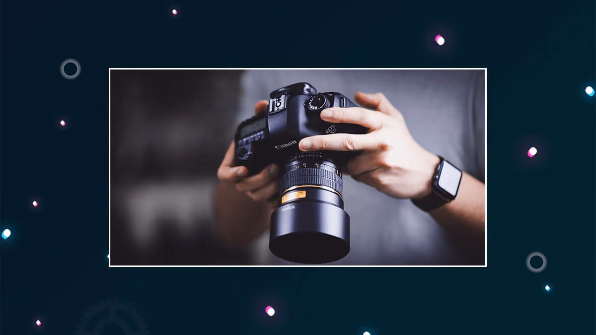 Person holding a Canon DSLR camera with a long lens.