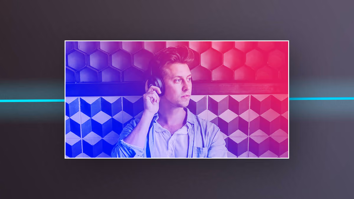 Man wearing headphones against a geometric wall with pink and blue lighting.