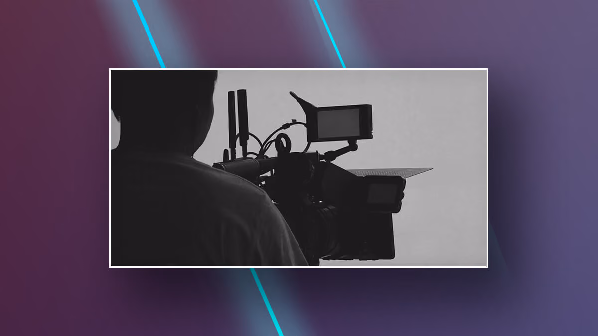 Silhouette of a person operating a professional video camera.